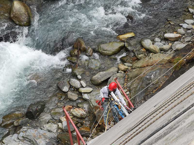 Homme descendant un mur de béton en rappel au dessus d'un cours d'eau