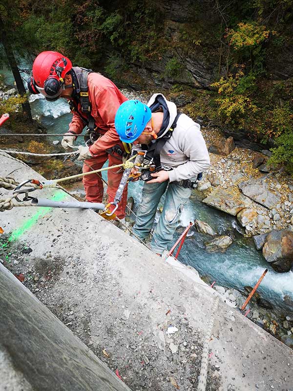 Deux ouvriers descendant un mur de béton en rappel